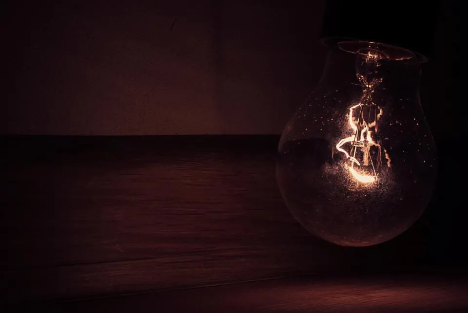 A filament bulb glowing faintly in a dark room