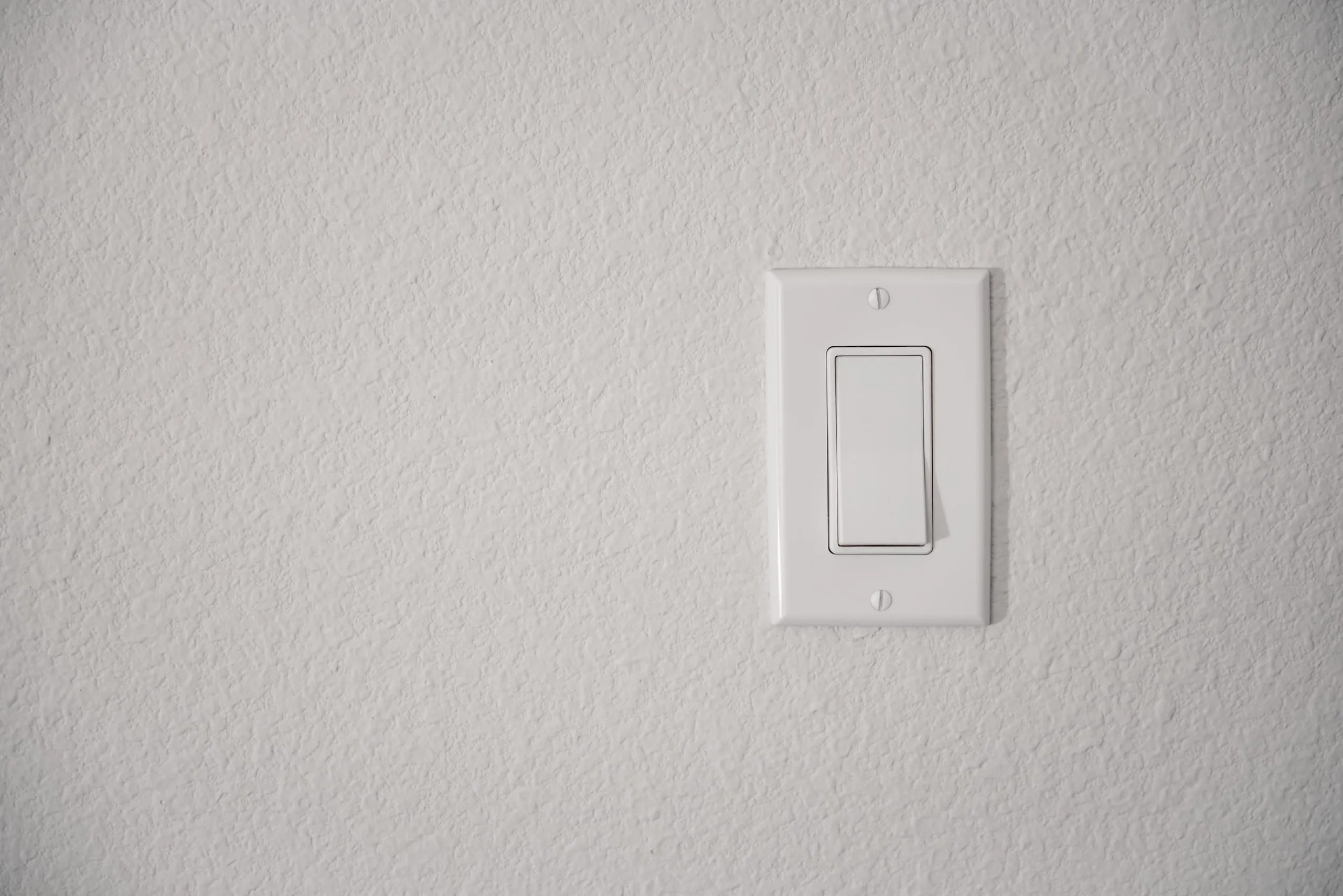 A white light switch on a plain white wall