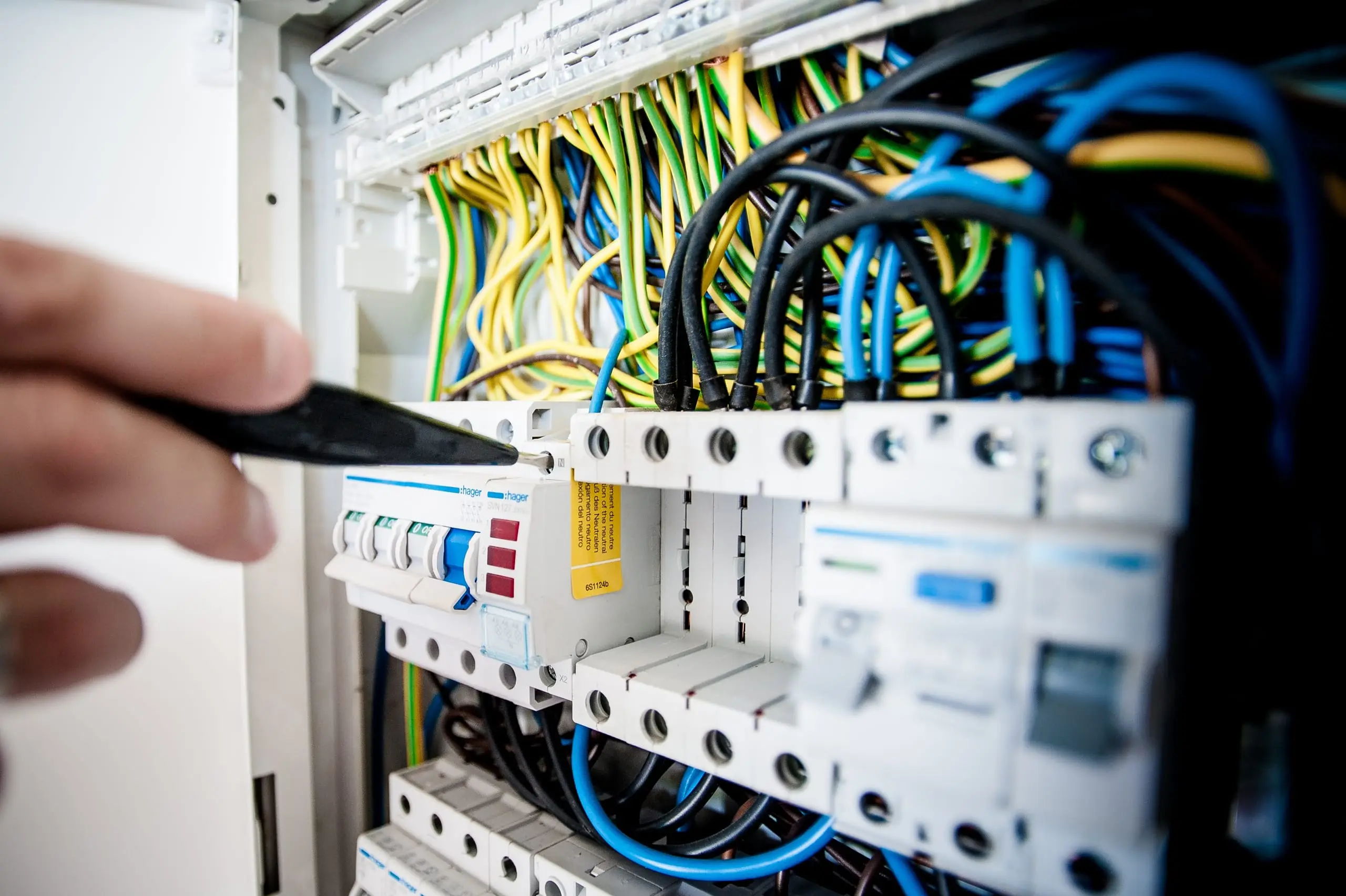 A tester probing the circuit breakers in an open switchboard